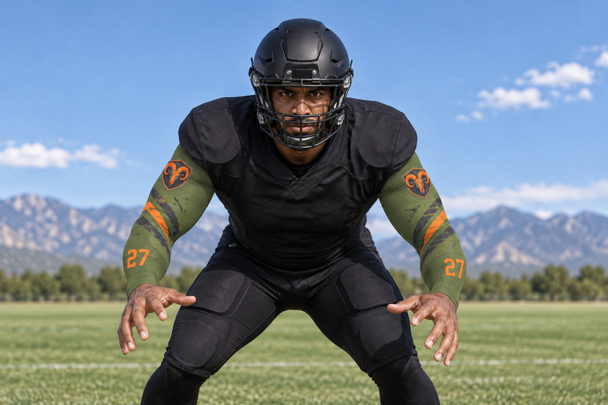 Linebacker in a ready stance in Army Green custom arm sleeves with a ram crest and number 27