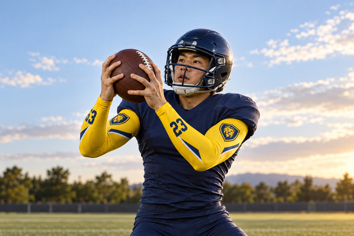 Football receiver securing a catch in Athletic Gold custom arm sleeves with a lion crest and number 23
