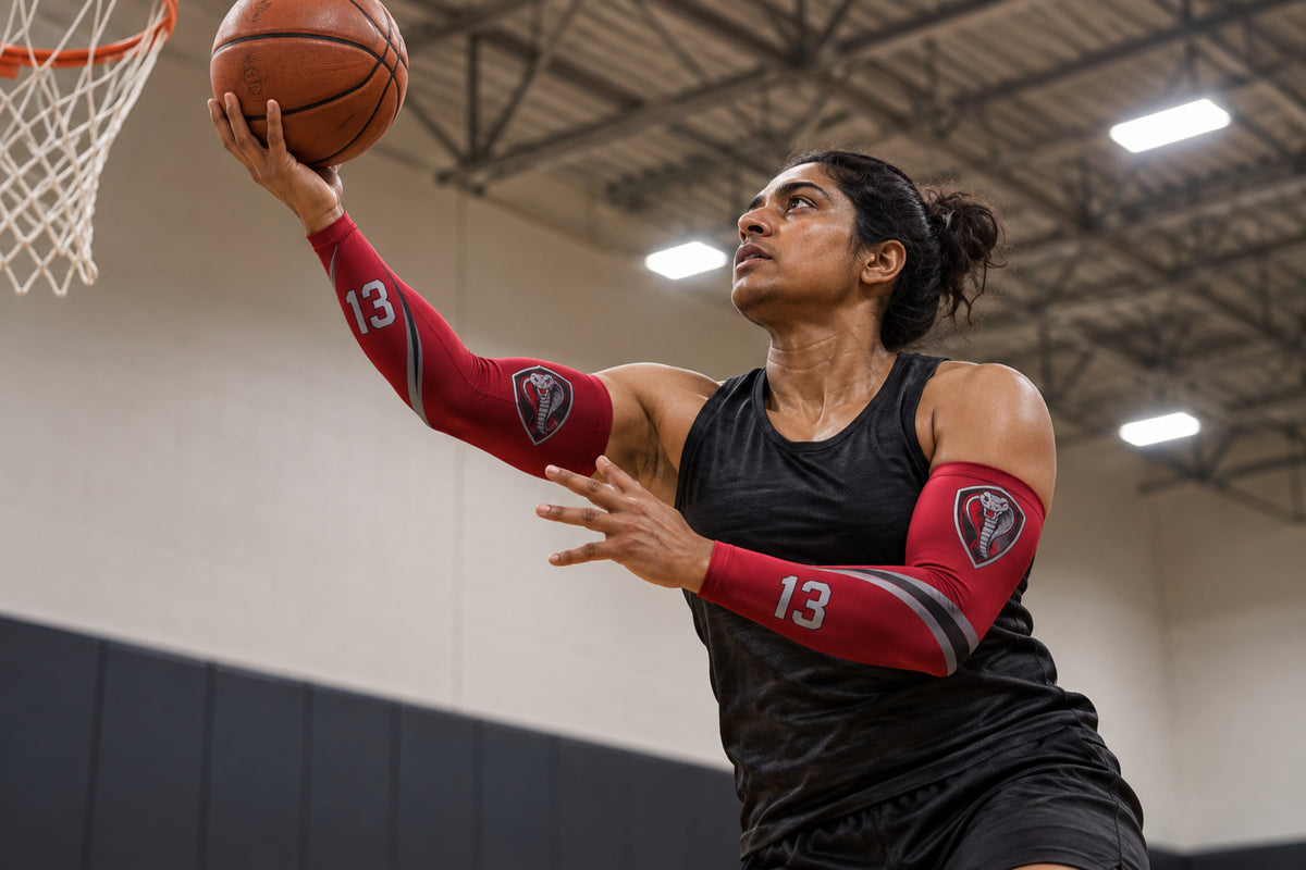 Basketball player finishing a layup in Cardinal Red custom arm sleeves with a cobra crest and number 13