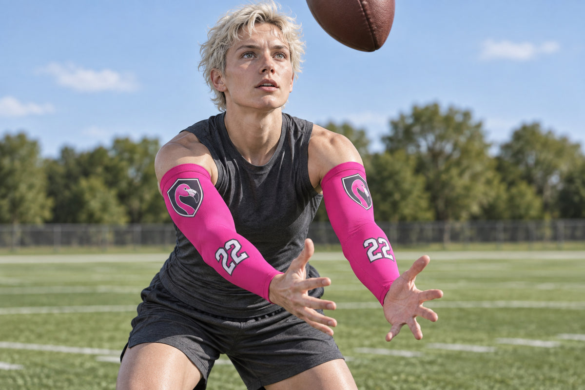 Football receiver reaching for the ball in Hot Pink custom arm sleeves with a flamingo crest and number 22
