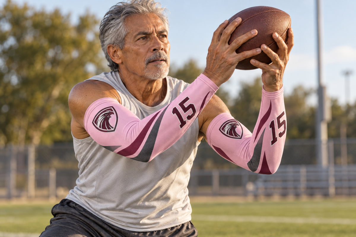 Football receiver making a two-hand catch in Light Pink custom arm sleeves with a falcon crest and number 15