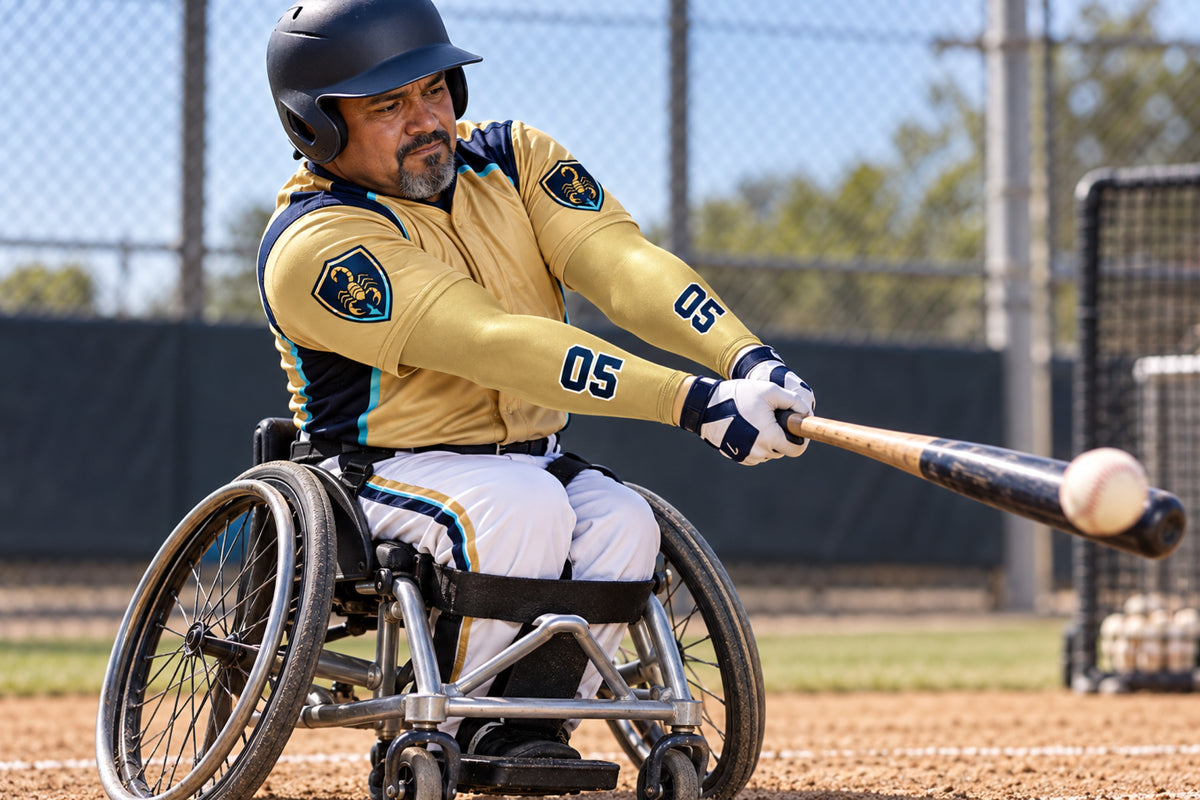 Seated adaptive baseball batter making contact in Vegas Gold custom arm sleeves with a scorpion crest and number 05