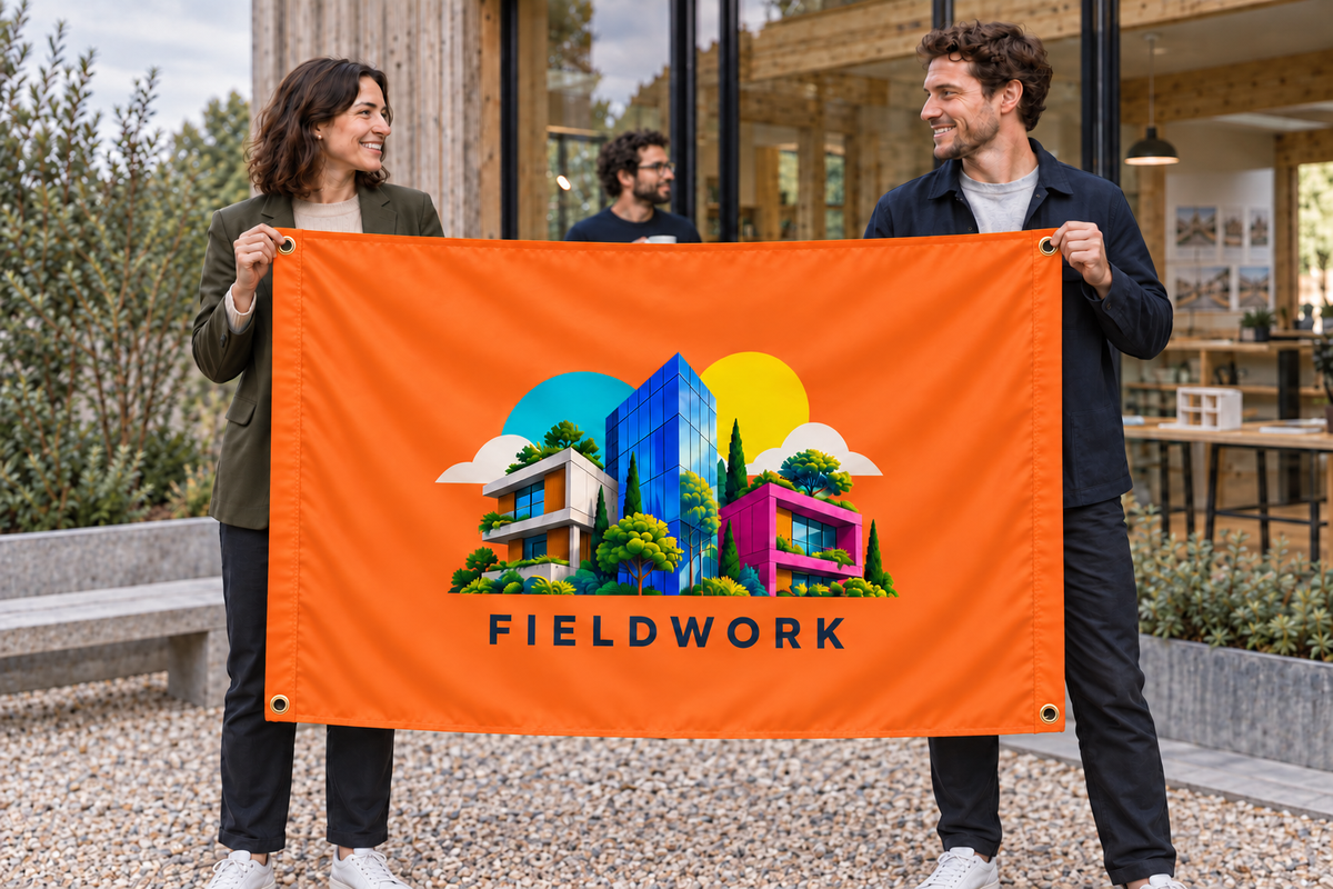 Illustrative campaign: adult business owners outside their workplace holding a customized orange flag, 5 feet wide by 3 feet tall with vivid multicolor artwork and four corner grommets