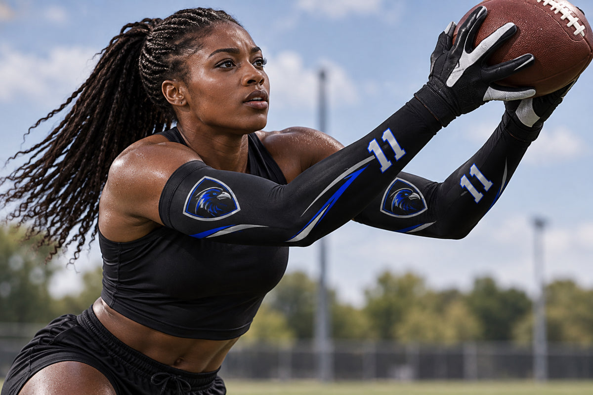 Football receiver making a two-hand catch in Black custom arm sleeves with a raven crest and number 11