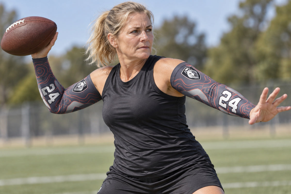Quarterback throwing a football in Charcoal custom arm sleeves with a wolf crest and number 24
