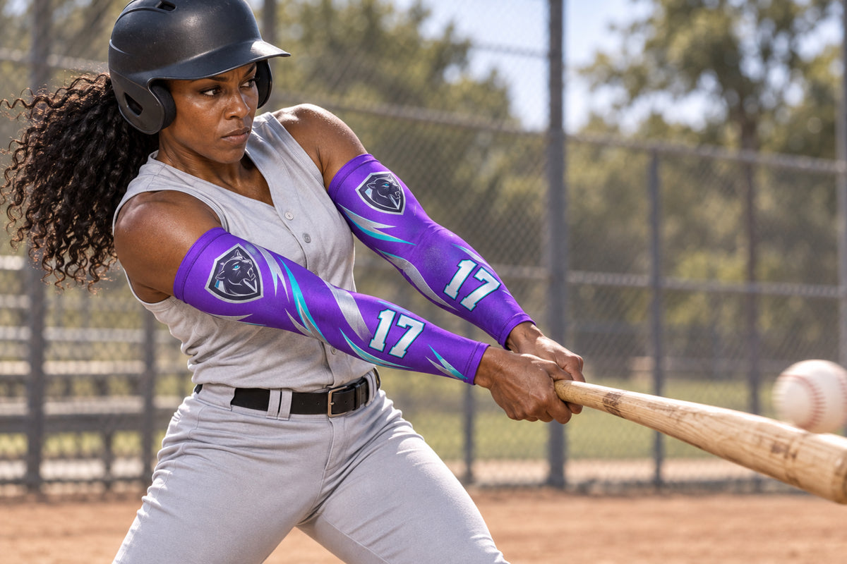 Batter completing a powerful swing in Purple custom arm sleeves with a panther crest and number 17