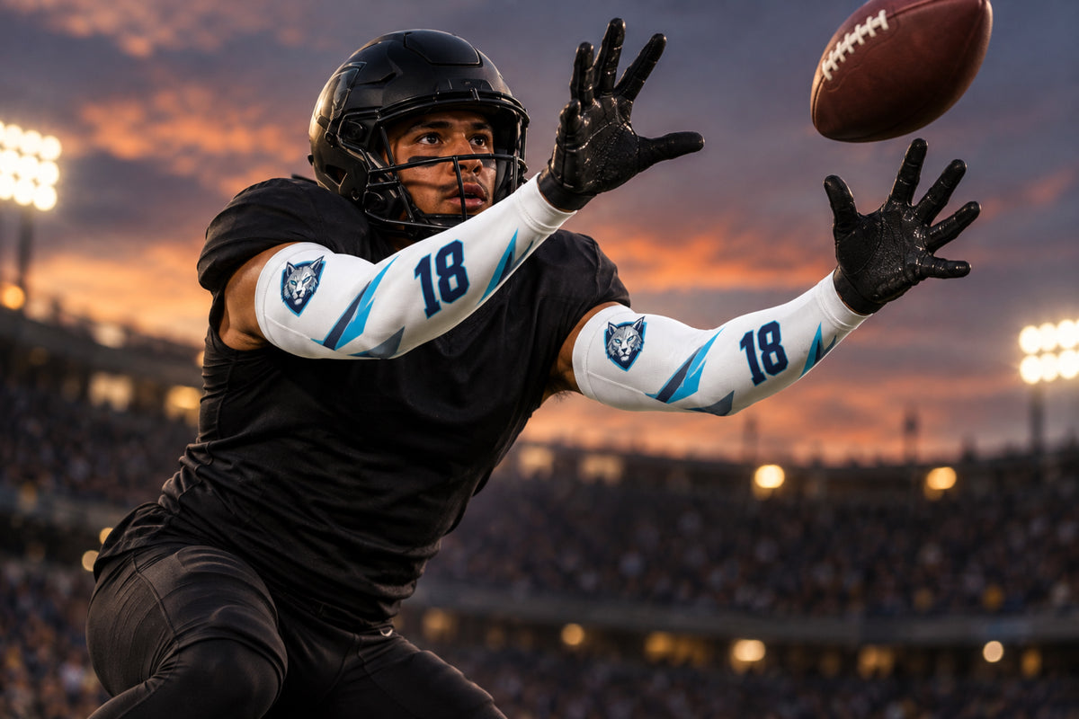 Football defensive back reaching for an interception in White custom arm sleeves with a lynx crest and number 18