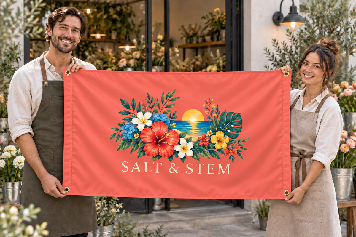 Illustrative campaign: adult business owners outside their workplace holding a customized coral flag, 5 feet wide by 3 feet tall with vivid multicolor artwork and four corner grommets