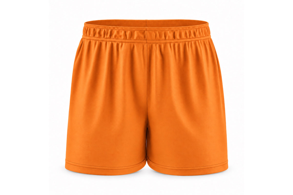 Front view of blank orange custom sublimated athletic shorts with elastic waistband and stitched hems on a white background.