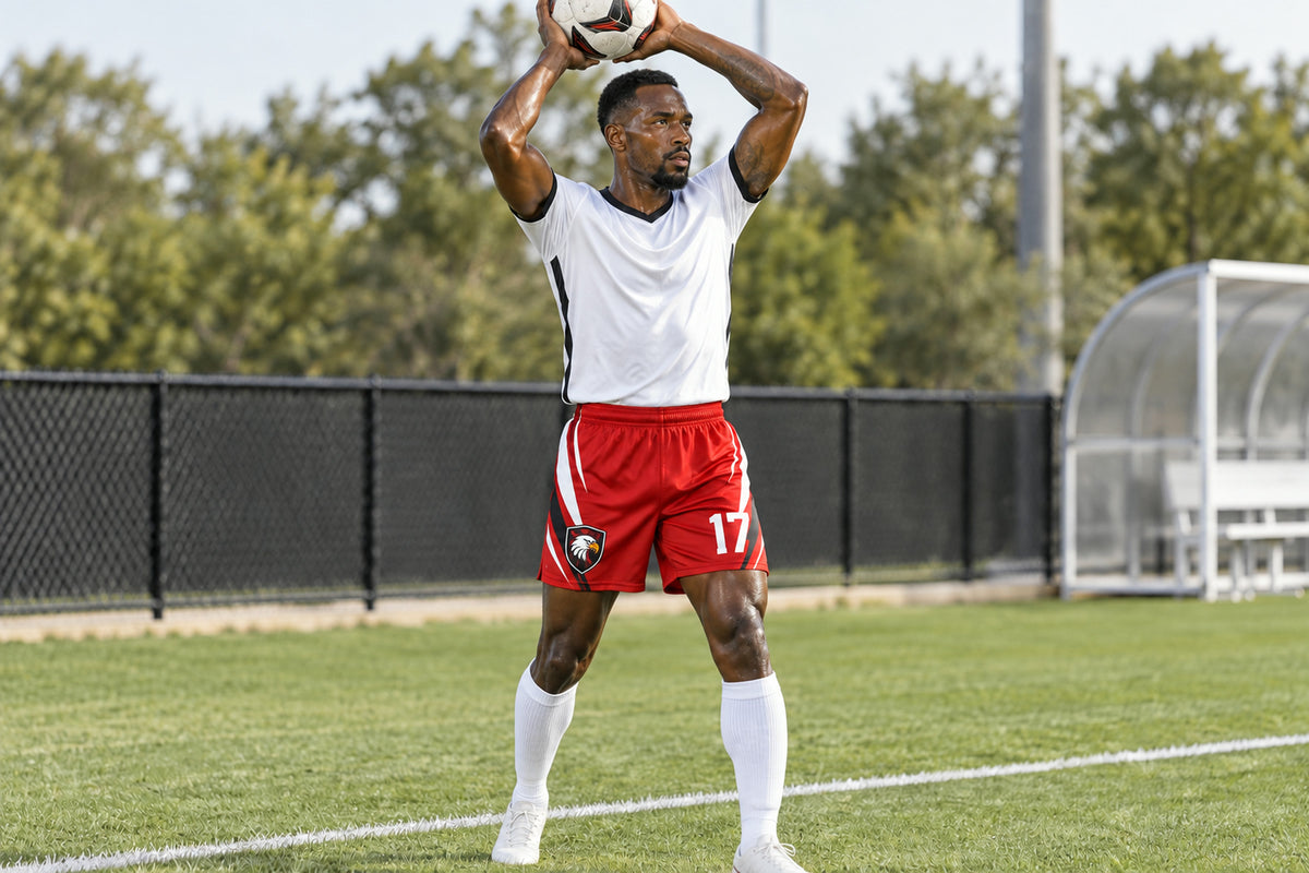 Soccer player executing a two-hand throw-in from the touchline wearing red custom sublimated athletic shorts with number 17.